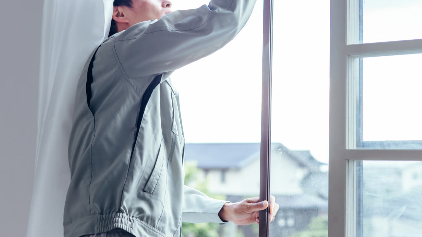 窓のメンテナンスをする作業服を着た男性